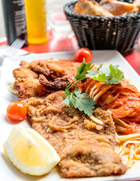 Close-up of cooked pasta with baby tomatoes and lemon served in plate