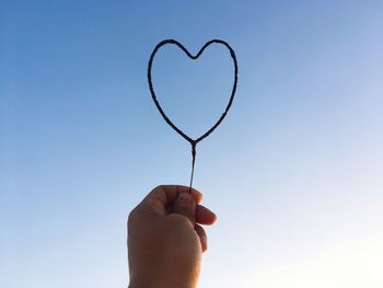 Close-up of person holding heart shape against clear sky