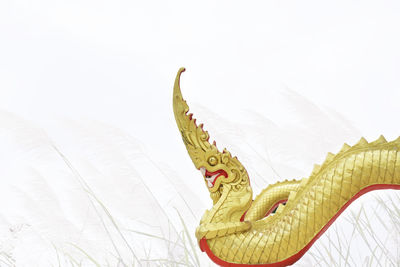 Golden naga statue isolated with blurred pampas grass background.