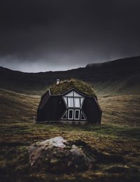 Built structure on field by mountain against sky