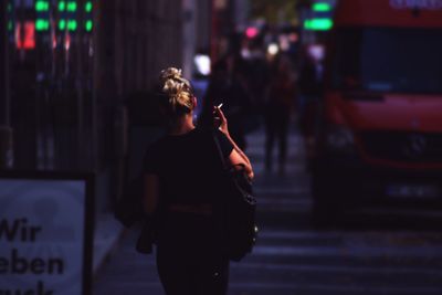 Rear view of woman standing on road at night