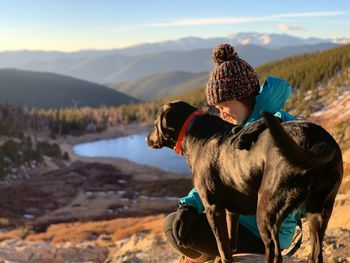 Rear view of horse sitting on land against mountains