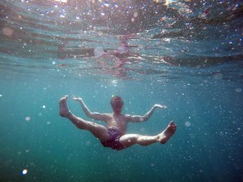 Full length of shirtless man swimming in sea