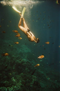 Woman free diving near nusa penida, bali, indonesia. nikonos v on 35mm cinestill 400d film.