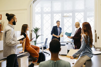 Businessmen discussing strategies with male and female colleagues at workplace