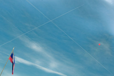 Low angle view of contrails at blue sky