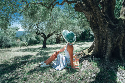 Woman in hat sitting on field