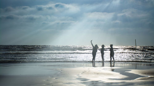 Silhouette of women taking selfie while standing at beach