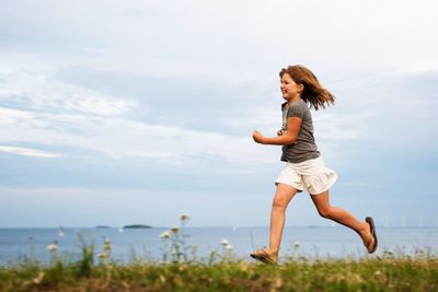 Girl running on field against sky