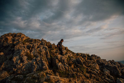 Man standing on rock against sky