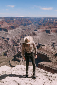 Full length of man standing on rock against sky