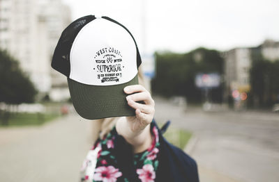 Portrait of woman holding hat in city