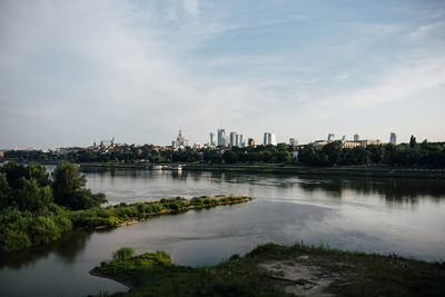 Scenic view of river by buildings against sky