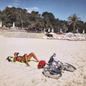 Shirtless man lying on picnic blanket at beach