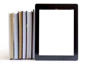Close-up of books with digital tablet over white background