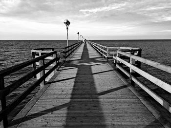 Pier on sea against cloudy sky