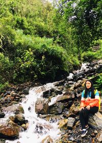 Young woman standing by stream in forest