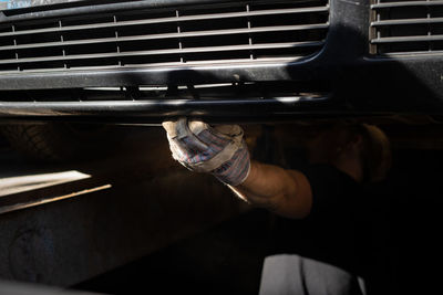 The mechanic services the car under the car