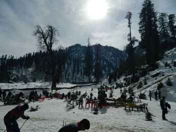 People on snow covered landscape against sky