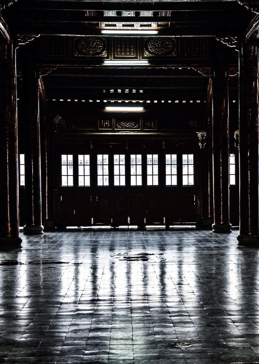 indoors, architecture, built structure, empty, flooring, architectural column, door, wood - material, corridor, interior, window, absence, closed, reflection, illuminated, building, no people, pattern, entrance, ceiling