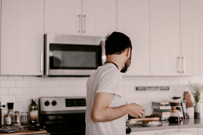 Side view of man standing in kitchen