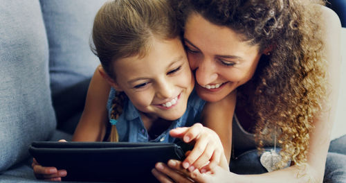 Smiling mother and daughter watching movie in digital tablet