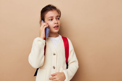 Portrait of young woman standing against pink background