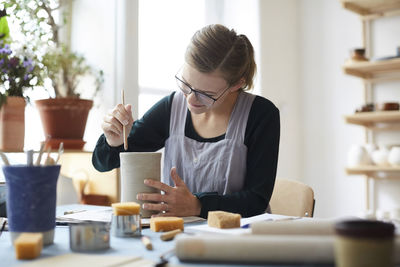 Young woman making earthenware in pottery class