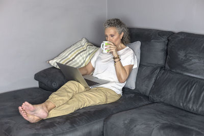 Full length of man sitting on sofa at home