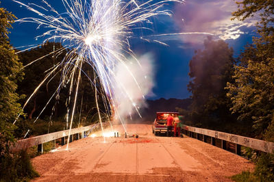 Firework display on street by car at dusk