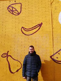 Portrait of young man standing against brick wall