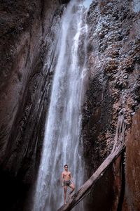 Woman standing on rock against waterfall