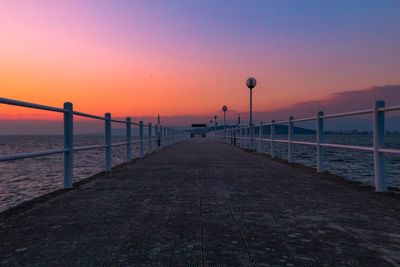 Pier over sea against clear sky during sunset