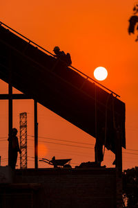 Low angle view of silhouette people on bridge against sky during sunset
