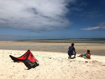 People sitting on beach against sky