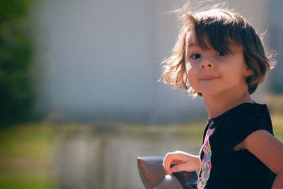 Low angle view of girl holding mobile phone outdoors