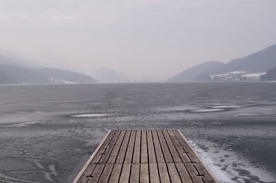 Scenic view of jetty over sea against sky during winter