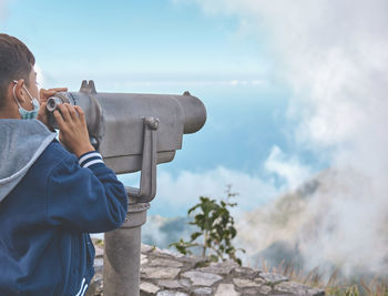 Tourist using binoculars looking at the city caracas from an observation point in the avila.