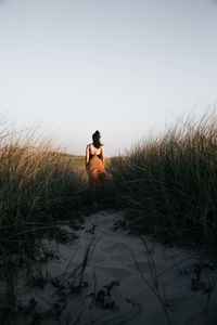 Rear view of woman standing on field against clear sky