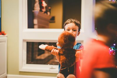 Boy holding christmas tree at home