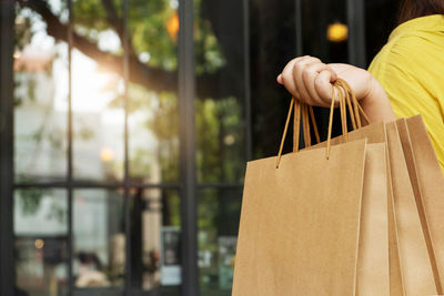 Midsection of person holding paper against store