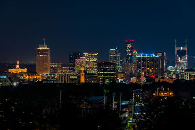 Illuminated buildings in city against sky at night