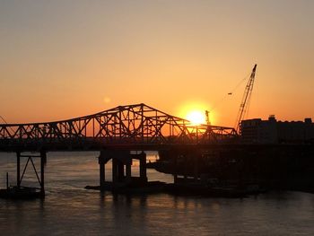 Silhouette bridge over sea against sky during sunset