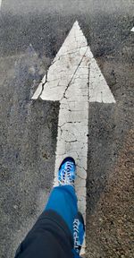 Low section of person with arrow sign on road