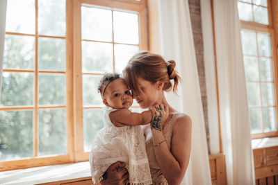 Happy mother and daughter against window