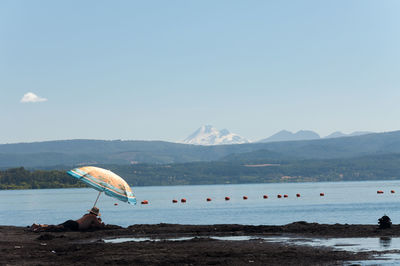 Scenic view of blue sea against mountain range