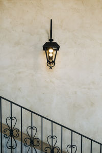 Low angle view of illuminated lamp mounted on wall