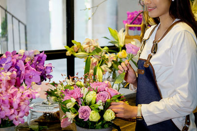 Midsection of female florist with flowers in store