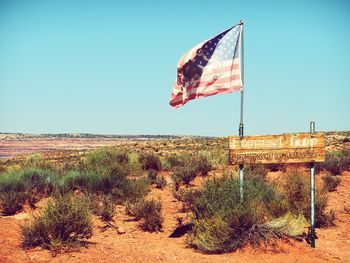 Flag on landscape against clear sky