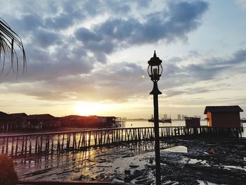 Street light by building against sky during sunset